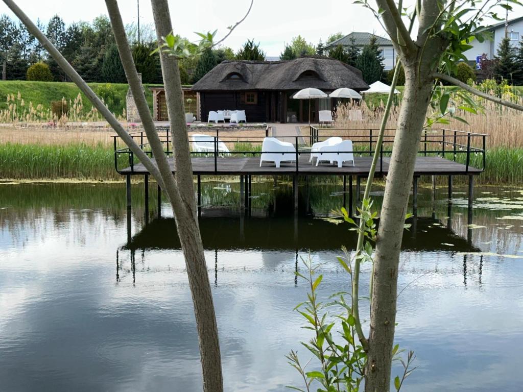 a dock with chairs and umbrellas on a body of water at Cabin by the pond in Wądołki Bućki