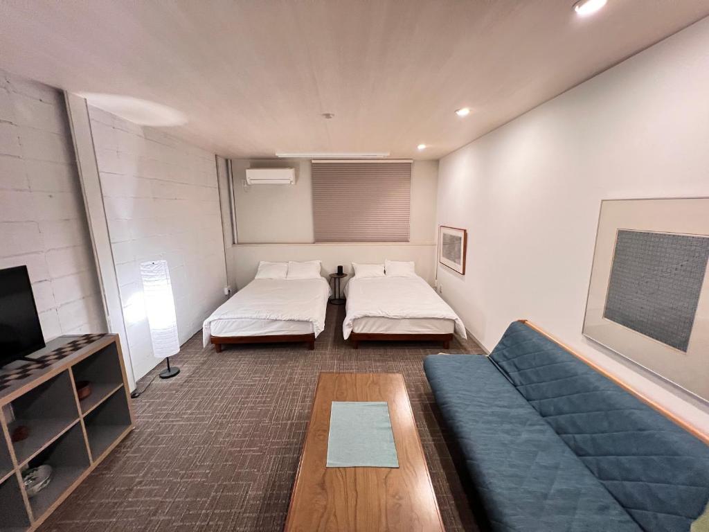 a room with two beds and a couch and a tv at 内町2階 1フロアまるごと貸切 高松中心部 4名まで in Takamatsu