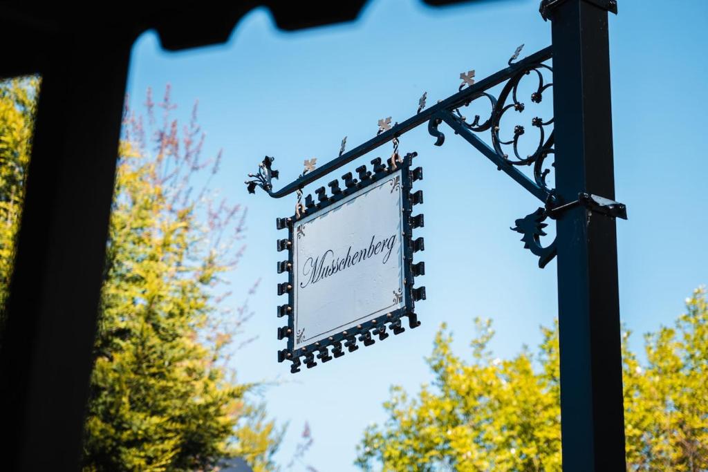 a sign hanging from a pole with trees in the background at Villa De Musschenberg in Beek