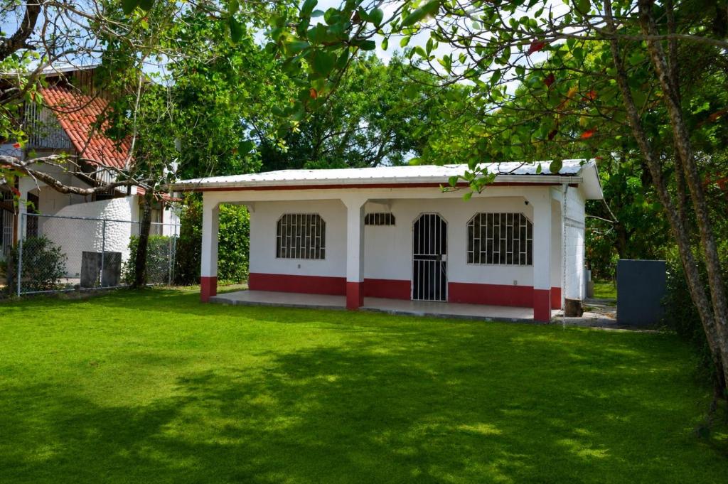 a white and red house with a green yard at Casa Osú in Sámara
