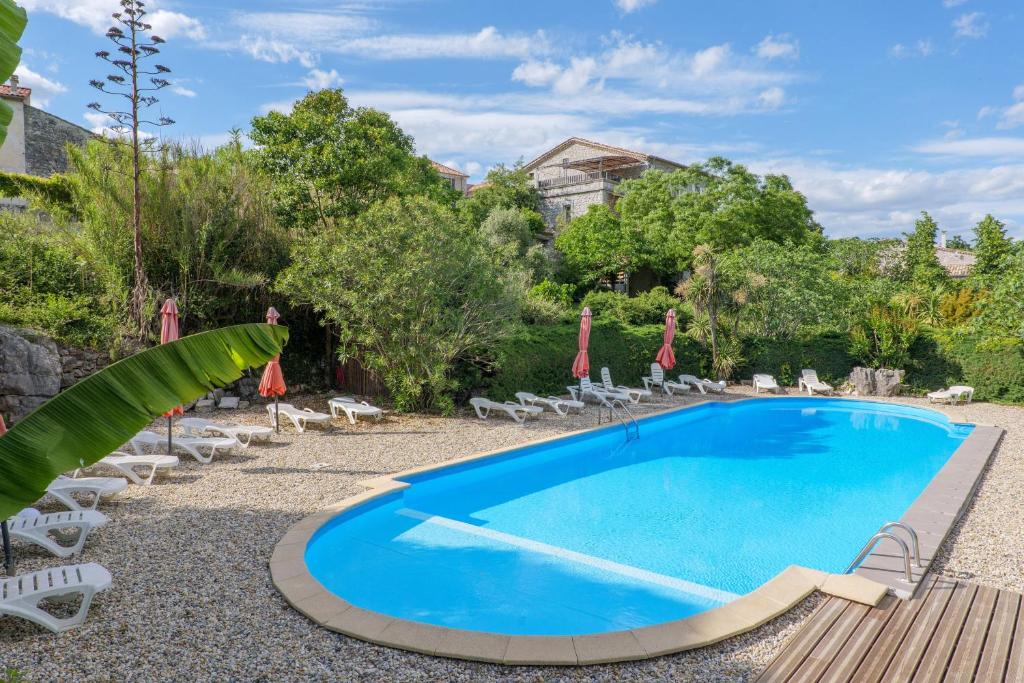 a pool with chairs and umbrellas in a yard at Le Mas Boyer in Chauzon