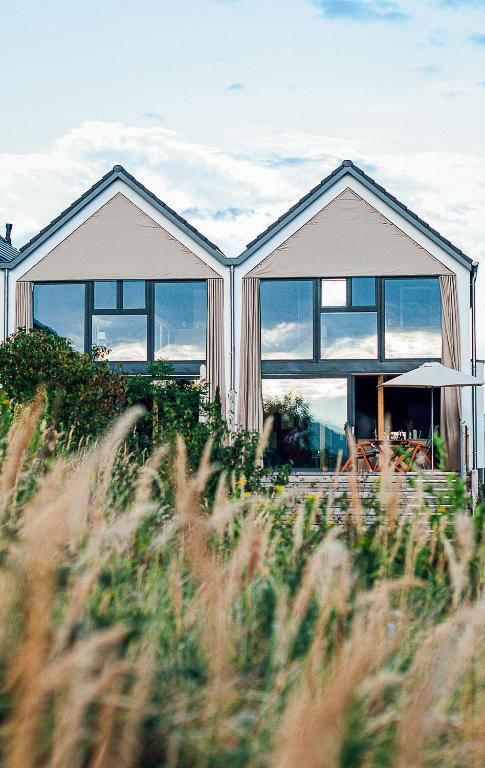 a house with large windows in a field of grass at Mosel Chalets - Design-Ferienhäuser - Terrasse und Traumblick, nähe Cochem - Direkt am Weinberg, Chalet Mitte mit Sauna in Pommern