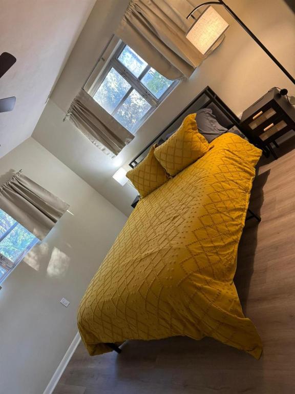 a large yellow bed in a room with windows at Vintage 2 Bedroom Condo Lake Eola View in Orlando