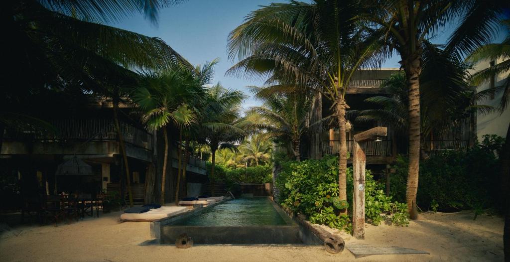 a pool in the middle of a resort with palm trees at BE Destination Tulum in Tulum