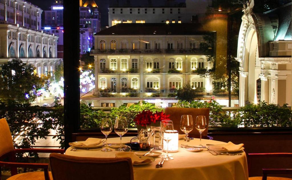 a table with wine glasses and a view of a building at Caravelle Saigon in Ho Chi Minh City