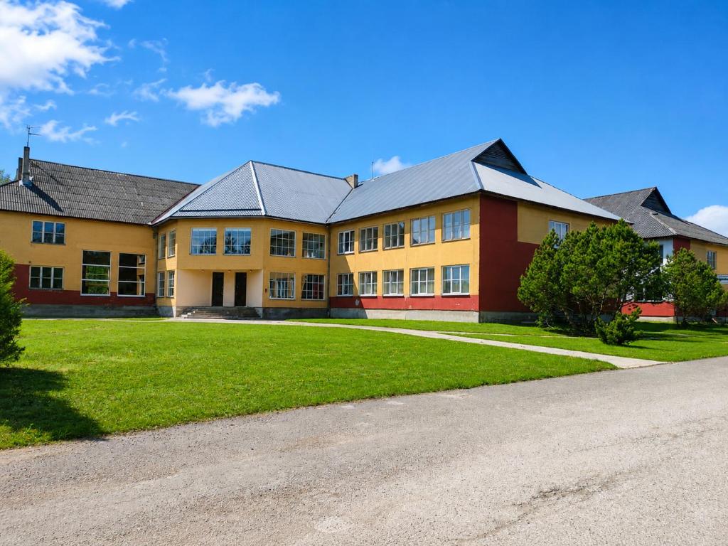 a large yellow and red building with a yard at Paide Event Center Hostel in Prääma