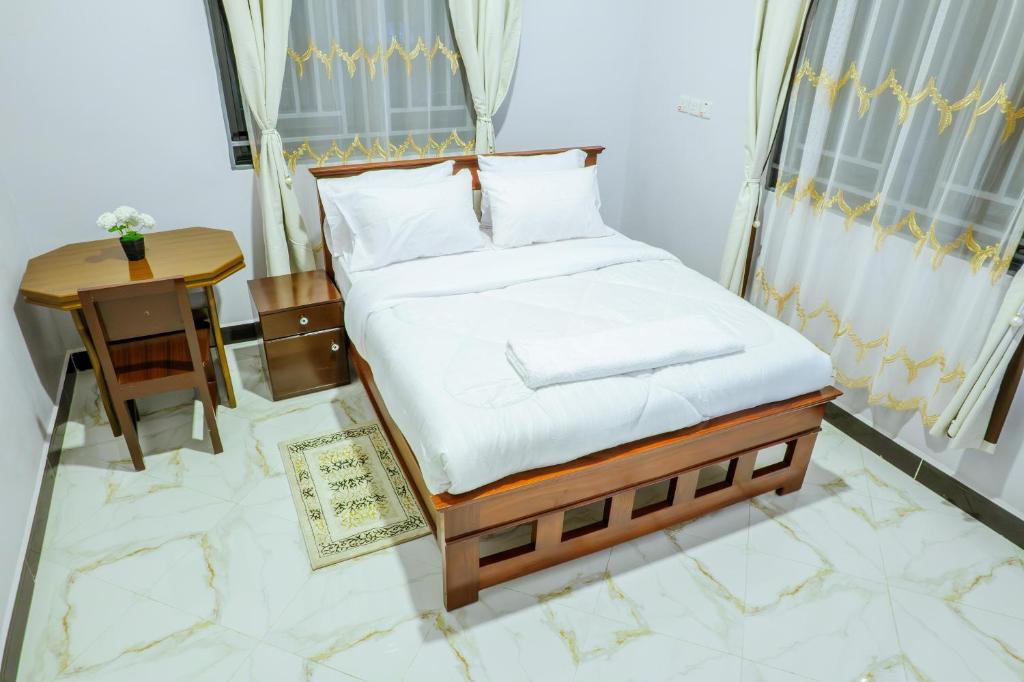 a bedroom with a bed and a table and a window at Cozycore Airnbn in Dodoma