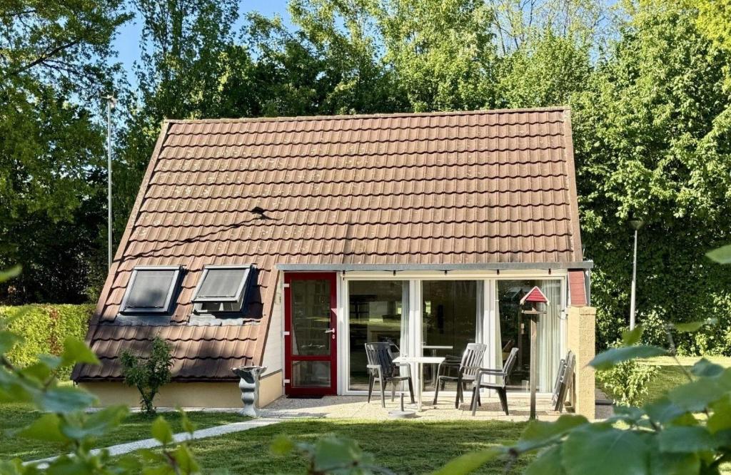 a small house with a table and chairs in a yard at Bungalowpark Simpelveld - Alpha 95 in Simpelveld