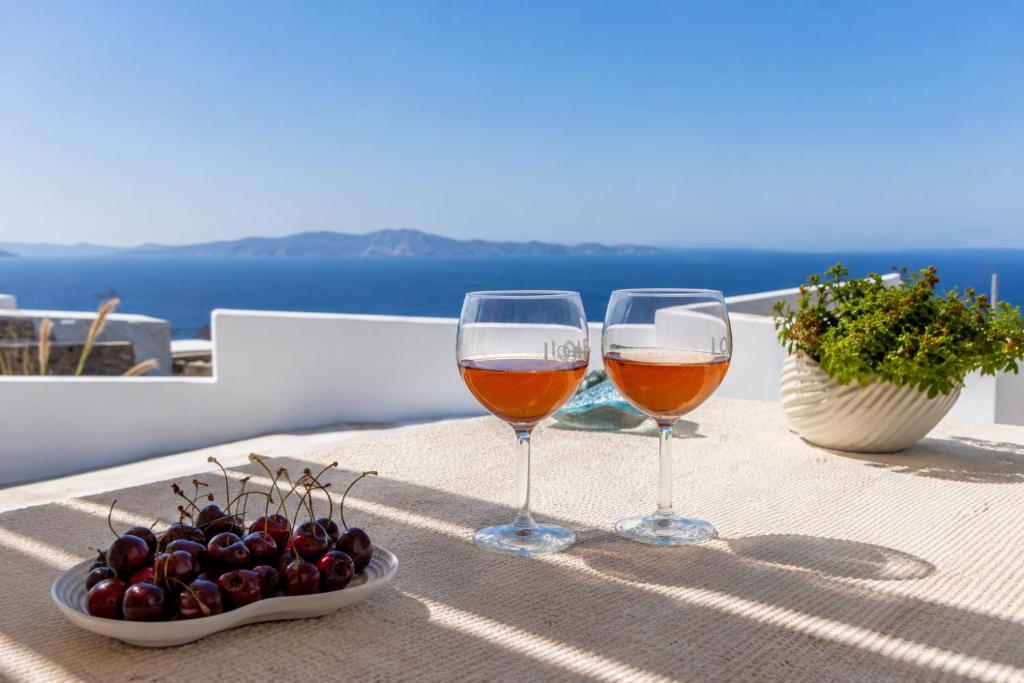 two glasses of wine sitting on a table with cherries at Tinian Sunset Villa in Istérnia