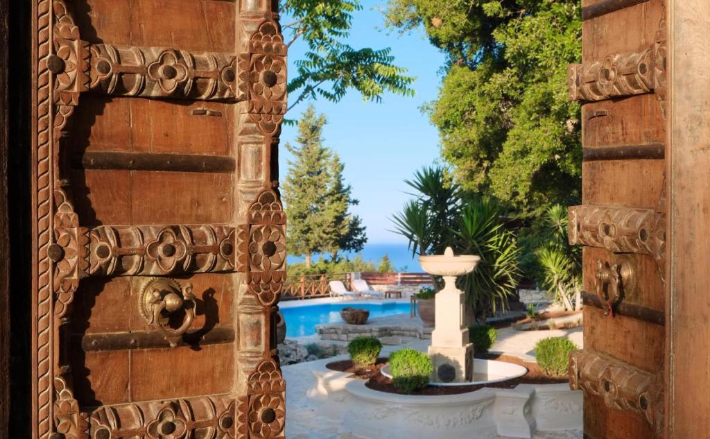 a view of a pool from a house with a stone wall at Purple Apricot Hotel in Vlachopoulátika