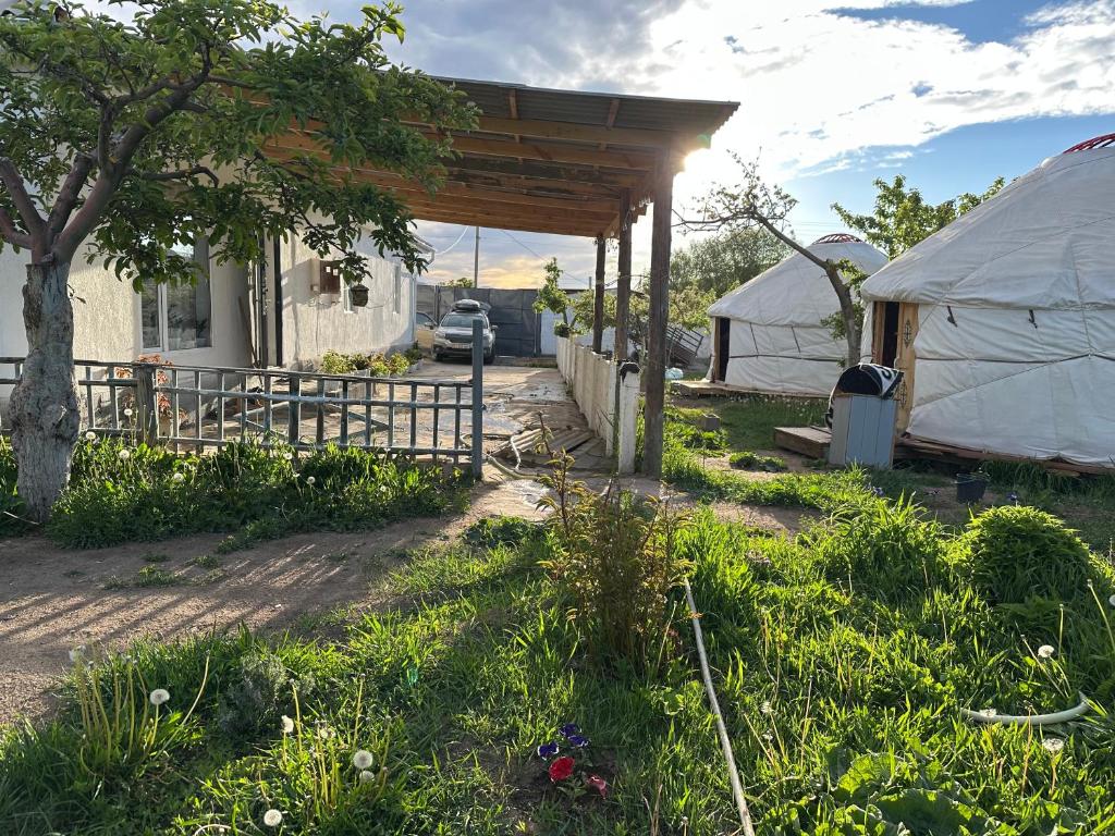 a yurt with a fence and a tree and a yard at Gulazyk guest house in Bokonbayevo