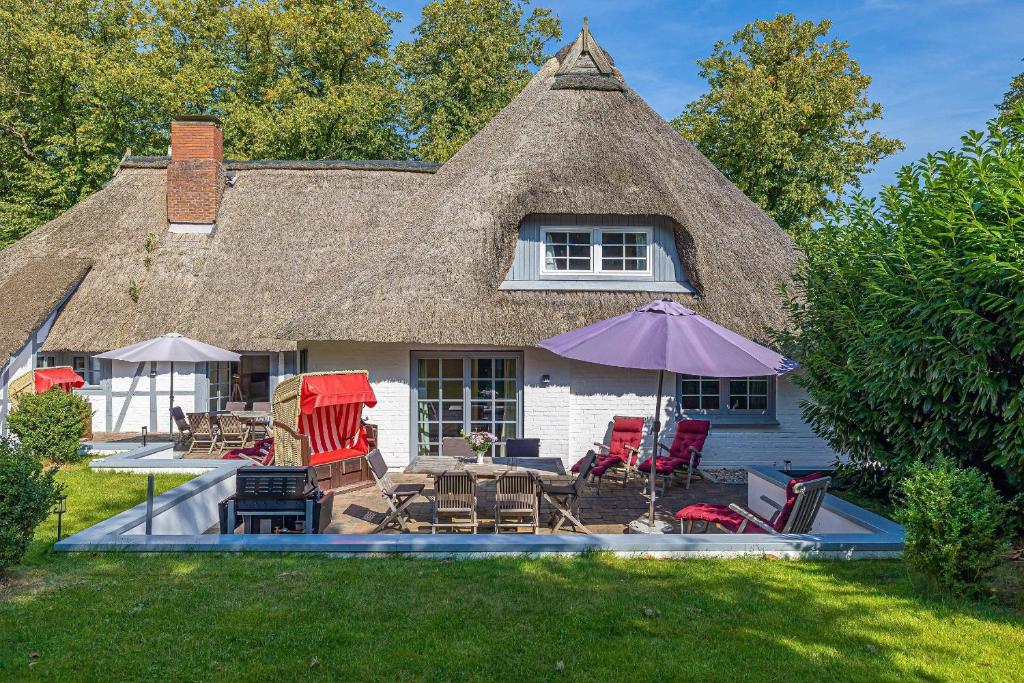 a house with a thatched roof with a table and chairs at Weiße Reetdachkate Wohnung 1 in Stöfs