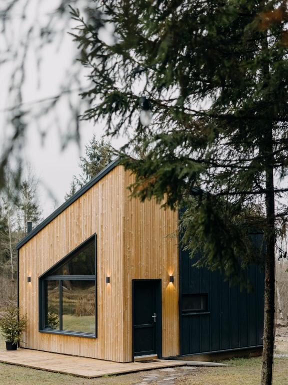a wooden building with a black door and a tree at Monside Resort - AIR CABIN in Borzont
