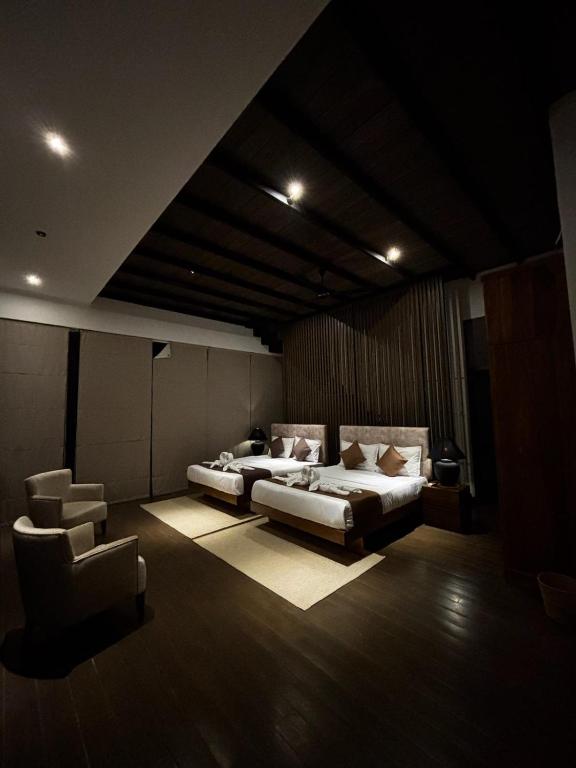 a room with two beds and a chair in it at Cinnamon Sunset Villa in Kurunegala
