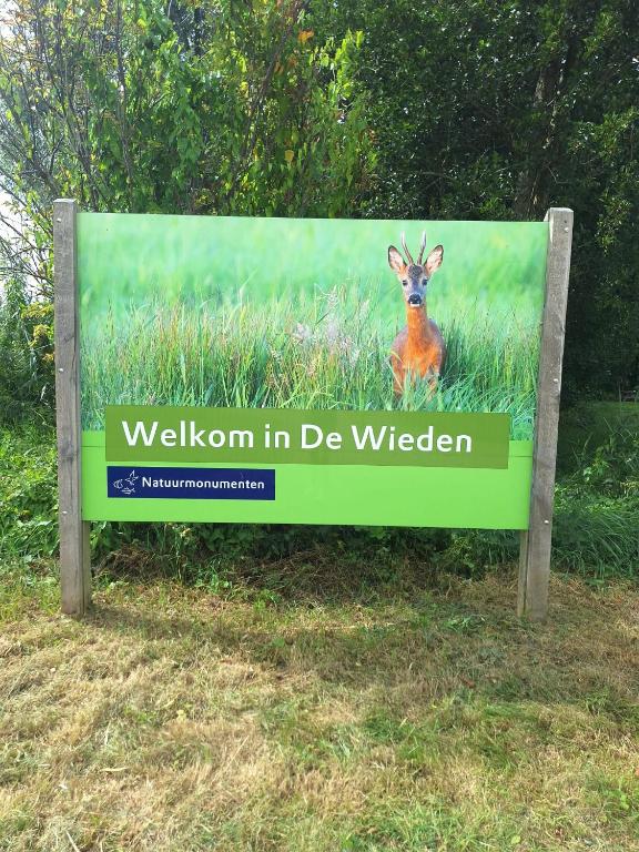 a sign with a deer sitting in the grass at De Kazerne - Beulaker wijde in Wanneperveen
