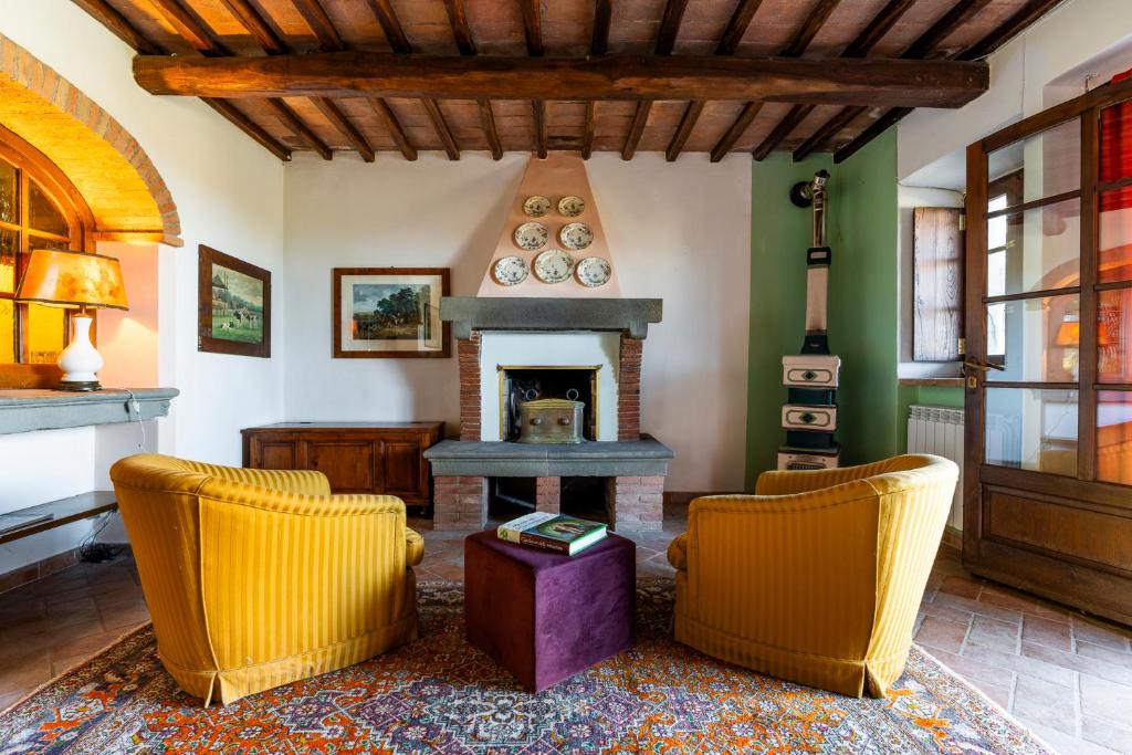 a living room with two chairs and a fireplace at La finestra sul Chianti in Radda in Chianti