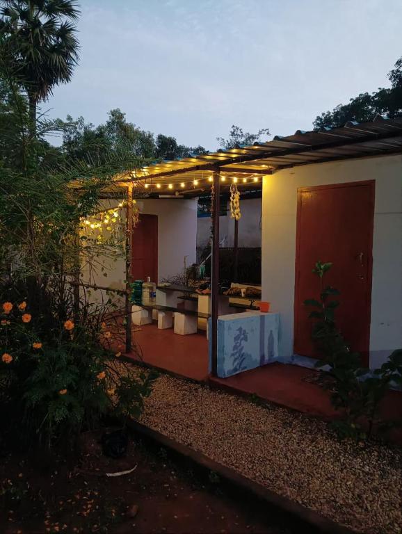 a house with a porch with lights on it at Rootscape Huts Hostel and Home Stay in Auroville