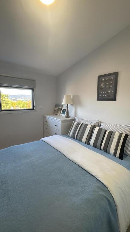 a bedroom with a blue and white bed and a window at Sunset Paradise in Caminha