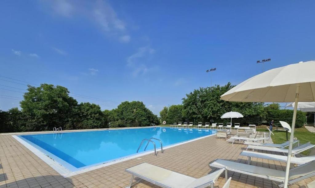 une grande piscine avec chaises longues et parasol dans l'établissement DESIGNcontrodesign, à Desenzano del Garda