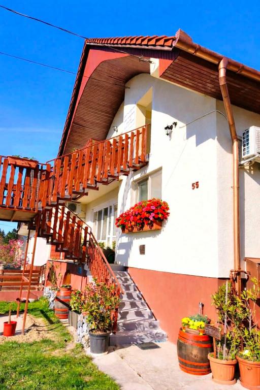 a house with a staircase and flowers on it at Liget Fruit Garden Family Apartman in Zalakaros