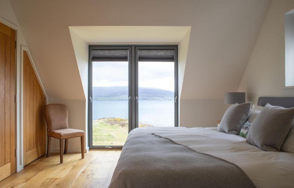 a bedroom with a bed with a view of the ocean at Cnoc Na Lobhta in Husabost