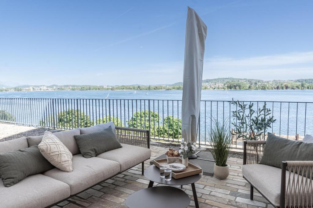 a living room with a couch and a view of the water at Casa Lago in Tüscherz-Alfermée