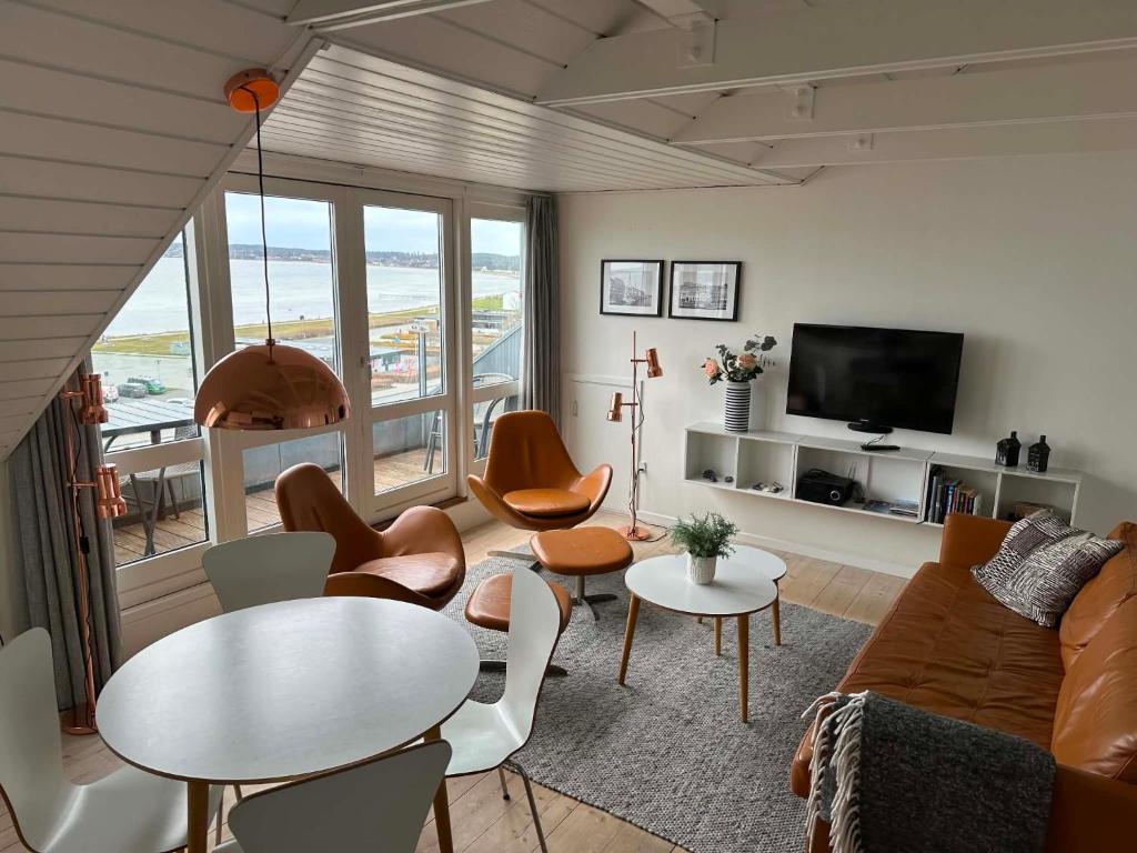 a living room with a couch and a table and chairs at Panoramaudsigt og swimmingpool midt i Ebeltoft in Ebeltoft
