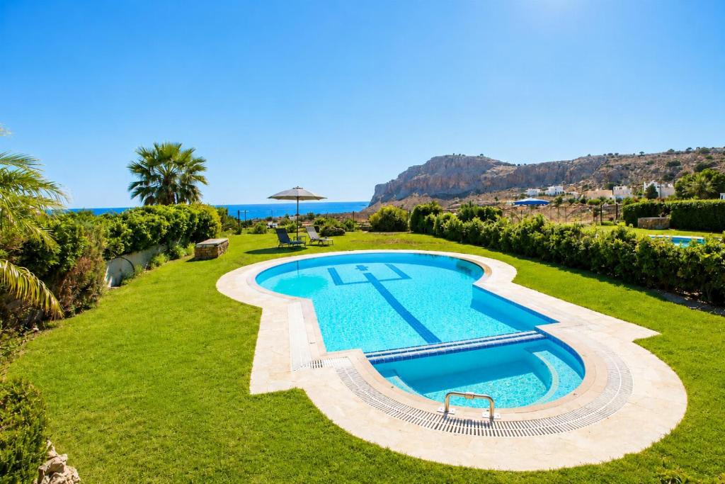 an image of a swimming pool in a yard with the ocean at Villa Driftwood in Rhodes Town