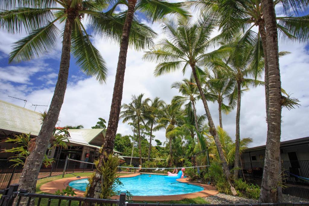 a pool with palm trees in front of a resort at Scotty's Mission Beach in Mission Beach