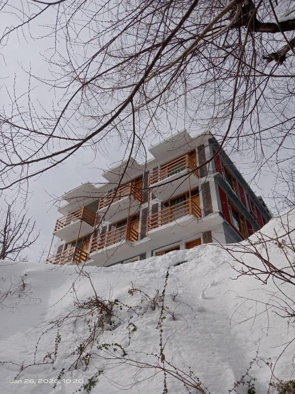 a building on top of a snow covered hill at Nimat Nivas By Fuwa Homestay in Vashisht