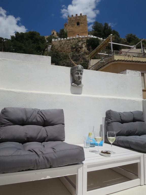a couch and a table with a glass of wine at Casa al Castillo - charming & authentic townhouse - terrace with stunning castle views in Cullera
