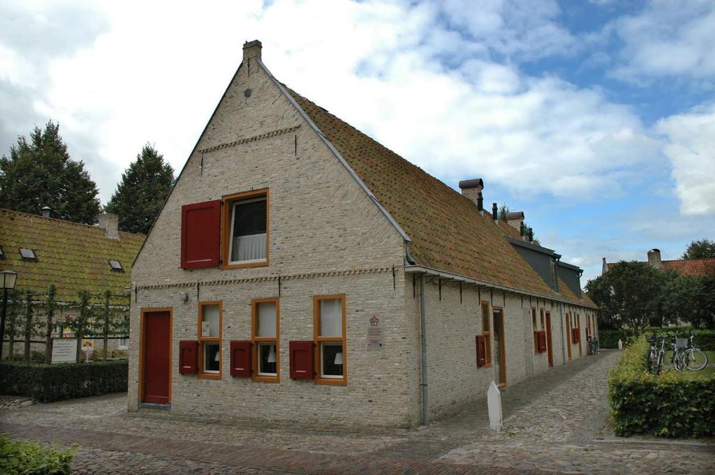 um edifício antigo com janelas vermelhas e um telhado em Hotel Vesting Bourtange em Bourtange