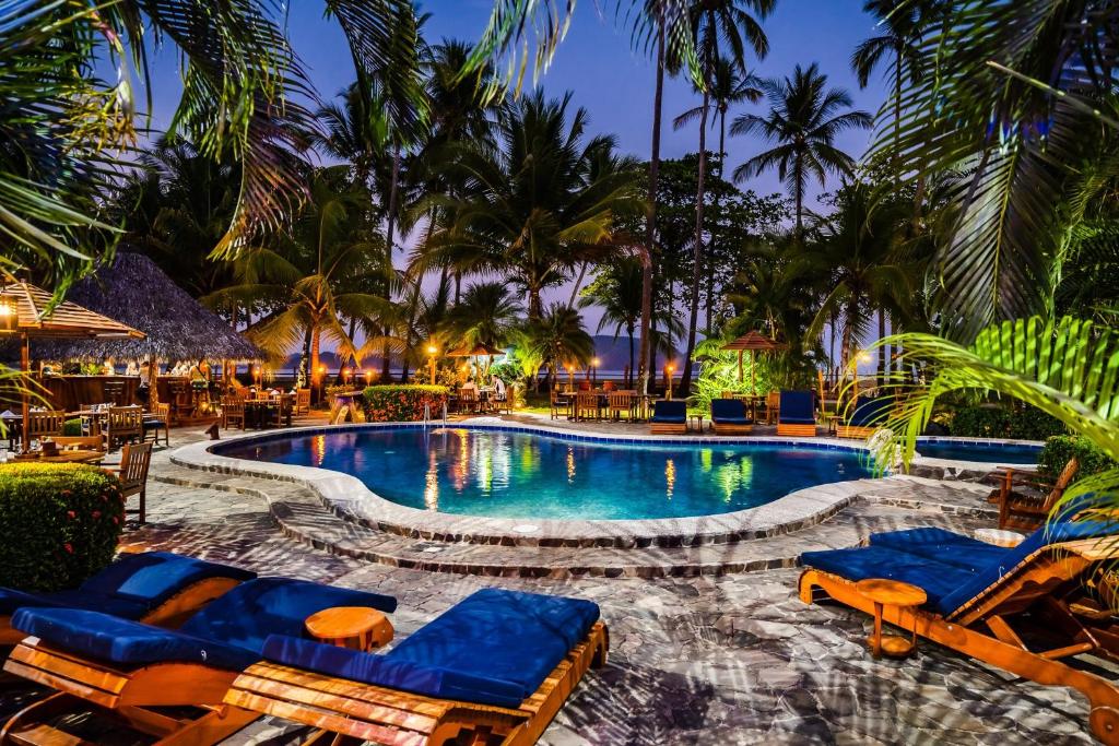a pool at a resort with chairs and palm trees at Tambor Tropical Beach Resort- Adults Only in Tambor