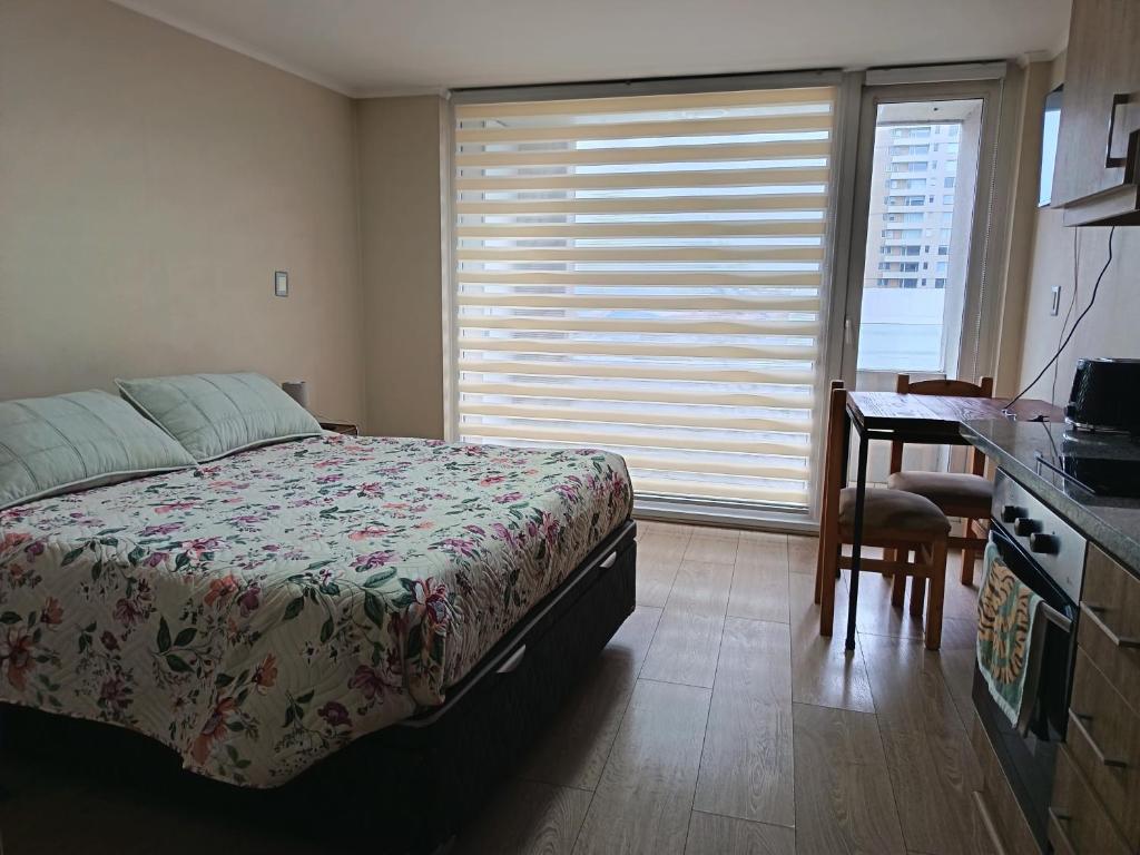 a bedroom with a bed and a desk and a window at Departamento Edificio Centro Osorno in Osorno