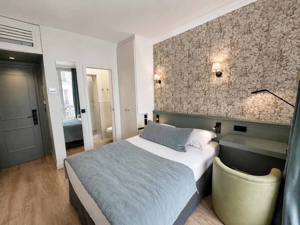 a bedroom with a bed and a stone wall at Hotel des Bains in Paris