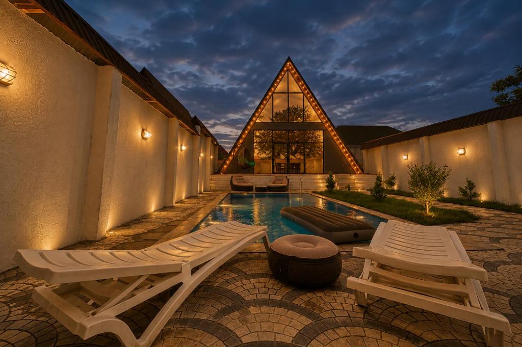 a swimming pool with two lounge chairs and a building at Gabala Twin Chalet in Gabala