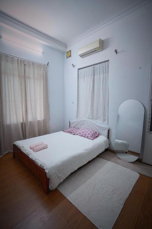 a white bedroom with a bed and a chair at Pawseas Homestay in Danang