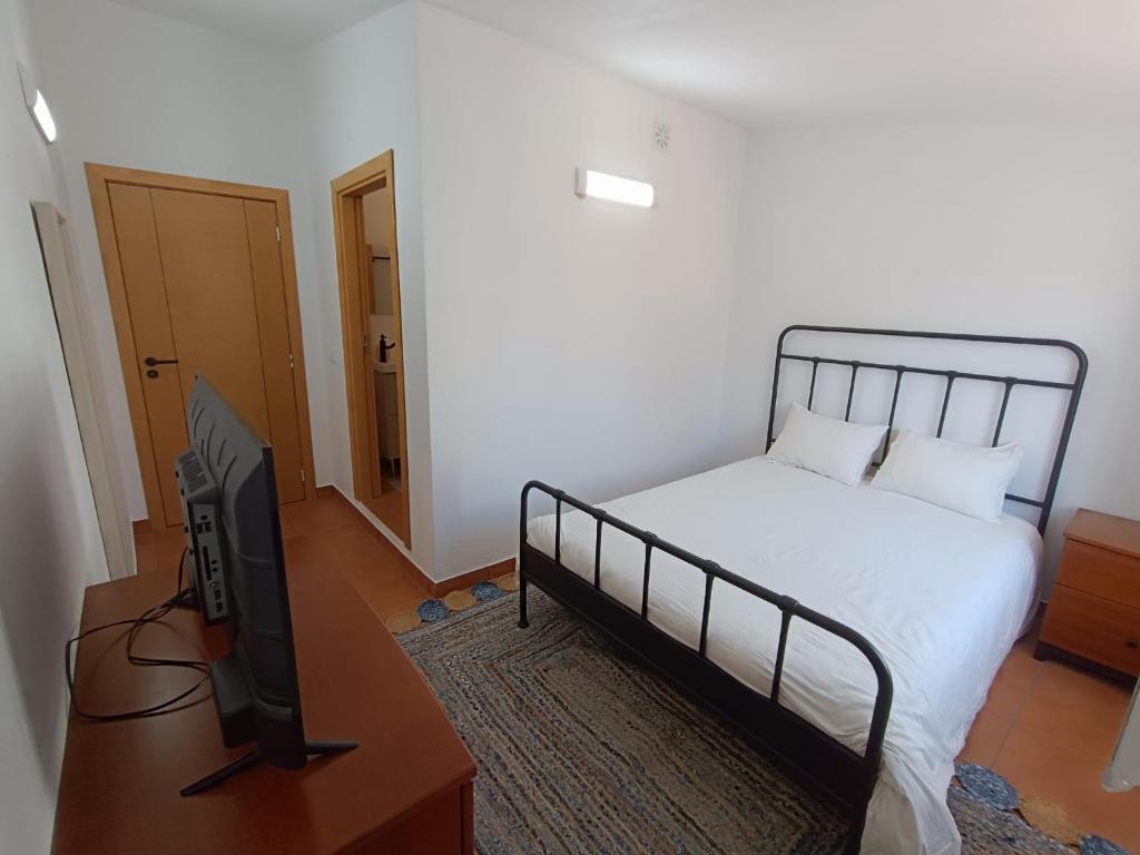 a bedroom with a bed and a flat screen tv at Casinha do Rui in Sines