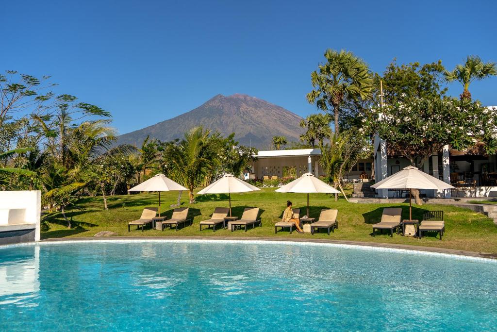 a pool at a resort with a mountain in the background at Palm Springs Bali Dive Resort in Tulamben