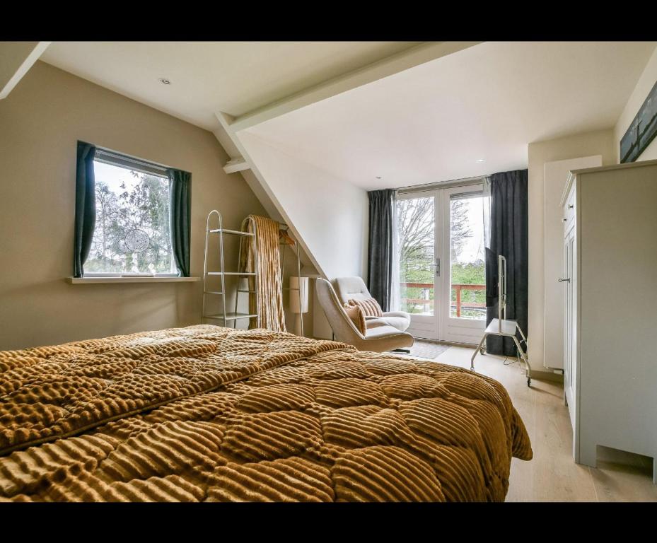 a bedroom with a bed and a chair and a window at The Rietvink Residence in Wervershoof