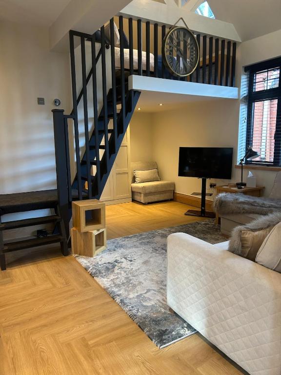 a living room with a staircase and a clock at Hawks Hideaway in Warminster