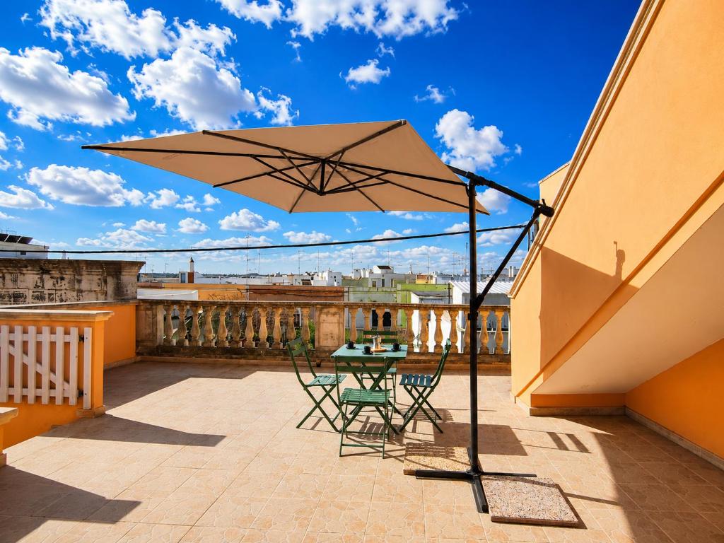 a patio with a table and chairs and an umbrella at Corte Dei Fiori Acquaviva Apartments in Marittima