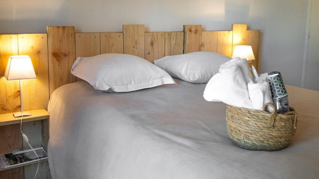 a large bed with two pillows and a basket on it at Hôtel du Bastier in Ginasservis
