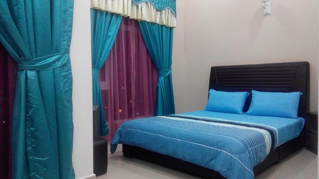 a bedroom with a bed with blue sheets and curtains at SAS D'PERDANA Apartment in Kota Bharu