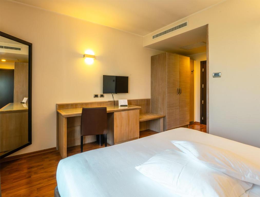ein Hotelzimmer mit Bett, Schreibtisch und Fernseher in der Unterkunft San Giorgio, Sure Hotel Collection by Best Western in Forlì