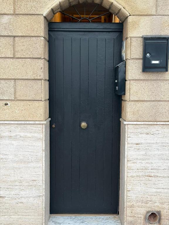 a black door in a building with a brick wall at B & B Yaya in Taranto
