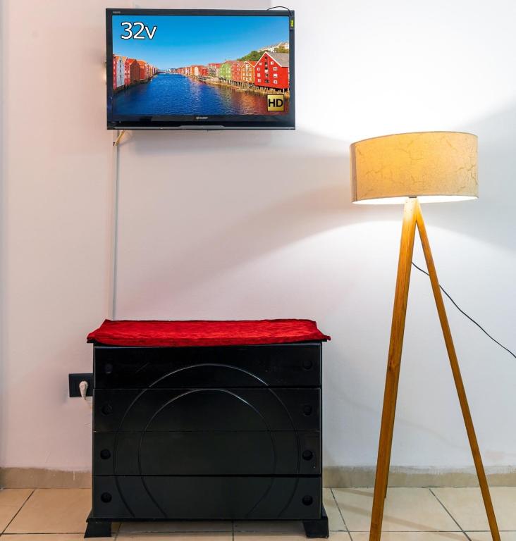 a flat screen tv on a wall next to a lamp at VIP Home in El Aouina Station