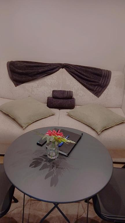 a table in front of a couch with a table with flowers on it at Luxury Studio - Romainville in Romainville
