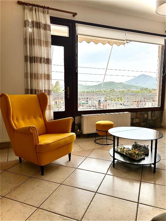 a living room with a yellow chair and a table at Lemon & Light Bright Apartment with View and Fireplace in Meligalás