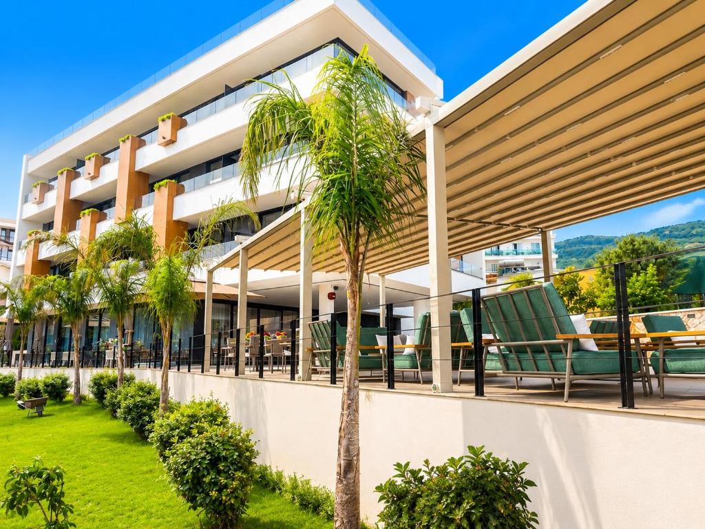 Außenansicht eines Gebäudes mit Palmen in der Unterkunft Green Light Hotel in Ksamil